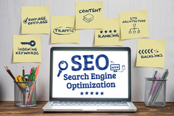 Image consist of Search Engine Optimization (SEO), prominently displayed on a laptop screen with several sticky notes around it. 