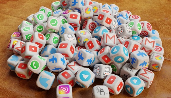 The image shows a pile of dice, each face displaying various social media and communication platform logos.